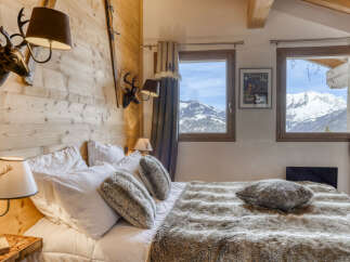Experience rustic charm and breathtaking mountain views from this cozy chalet bedroom.