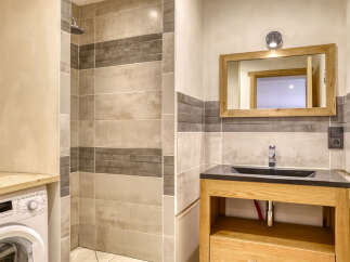This modern bathroom features a sleek shower area with horizontal tiling and a convenient washing machine.