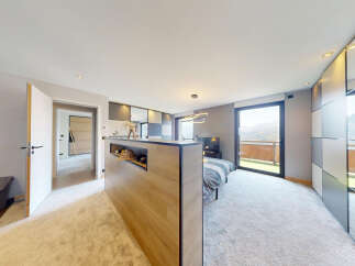 Experience luxury mountain living in this stunning studio apartment, featuring a modern open-plan layout with a comfortable bed and a sleek kitchenette.