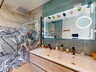 Experience modern luxury in this stunning bathroom featuring a double vanity with sleek wooden cabinetry and a large, illuminated mirror.