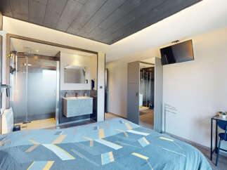 Experience modern comfort in this stylish bedroom featuring a sleek, open-plan bathroom with a glass-enclosed shower and a floating vanity.
