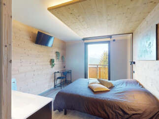 Experience cozy mountain living in this charming bedroom featuring warm wood paneling and a comfortable bed.