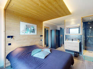 Experience modern alpine living in this stylish bedroom featuring a cozy bed with plush pillows and a striking abstract artwork.