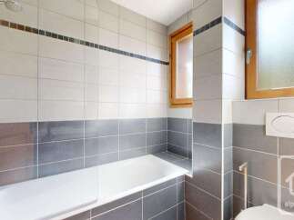 This modern bathroom features a sleek bathtub with a chrome showerhead, perfect for relaxing after a long day.