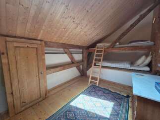 Discover this charming attic room featuring a cozy bunk bed setup, perfect for maximizing space.
