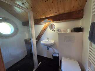 This charming bathroom features a unique circular window and exposed wooden beams, adding rustic character.