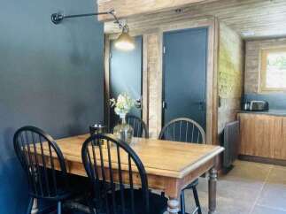 This charming dining area features a rustic wooden table with four black spindle-back chairs, perfect for intimate meals.