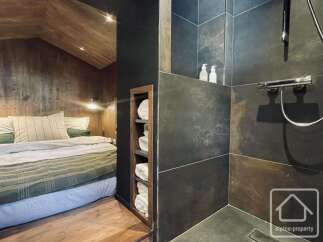 Experience rustic luxury in this charming bedroom featuring a cozy bed with plush linens and a unique wooden ceiling.