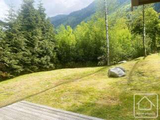 Enjoy the serene mountain landscape from this property's expansive lawn, perfect for outdoor activities or simply relaxing.