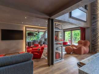 Experience luxurious living in this modern lounge area, featuring vibrant red armchairs and a unique striped accent chair.