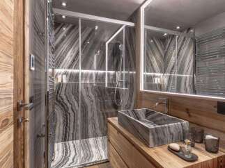 Experience luxury in this modern bathroom featuring a striking marble shower with integrated lighting and a sleek glass enclosure.