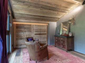 Experience rustic charm in this inviting living space, featuring a cozy leather armchair and a plush pink rug.