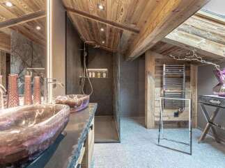 Experience rustic luxury in this stunning bathroom, featuring unique stone vessel sinks and a spacious walk-in shower with modern fixtures.