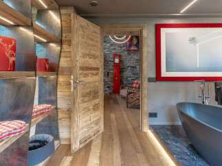 Experience rustic luxury in this stunning mountain retreat, featuring a spacious bathroom with a freestanding tub and a large framed artwork.