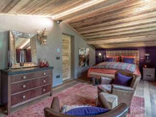 Experience rustic luxury in this charming bedroom, featuring a cozy plaid comforter and a rich, dark wood dresser.