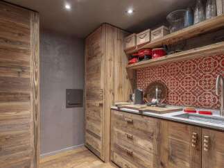 Experience rustic charm in this beautifully appointed kitchen, featuring custom wooden cabinetry and a striking red patterned backsplash.