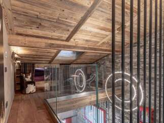 Experience luxury mountain living in this stunning chalet, featuring a rustic wooden ceiling and stone accent walls.