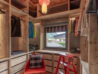Discover this charming walk-in closet, featuring rustic wooden shelving and ample storage for all your apparel.