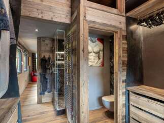 Experience rustic luxury in this mountain retreat, featuring a unique walk-in closet with exposed wooden beams and a modern aesthetic.