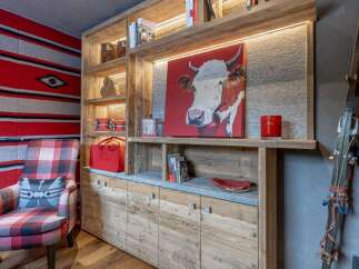 Experience rustic charm and cozy mountain living in this inviting space, featuring a striking cow portrait above a wooden cabinet.
