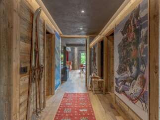Experience rustic charm in this mountain retreat hallway, featuring warm wooden paneling and vintage skis as decor.