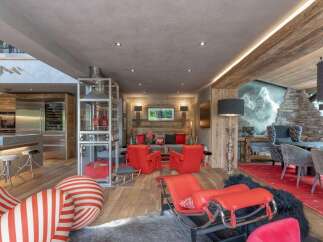 Experience luxury mountain living in this stunning chalet, featuring a modern open-plan kitchen with stainless steel appliances and a wine fridge.