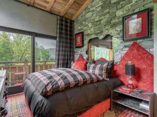 Experience rustic luxury in this charming bedroom, featuring a cozy bed with plaid bedding and a striking stone accent wall.
