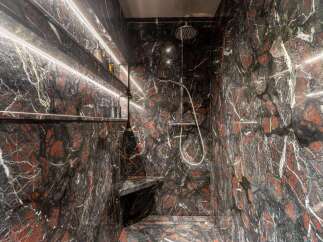 Experience luxury in this stunning shower featuring dramatic black and red marble walls.