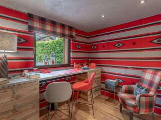 This cozy home office features vibrant red and gray striped walls with a Southwestern-inspired pattern, creating a unique and energetic atmosphere.