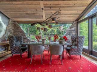 Experience luxurious mountain living in this stunning dining room, featuring a rustic stone accent wall and a unique branch chandelier.