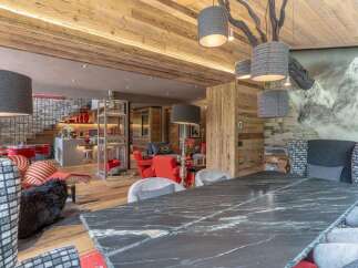 Experience luxurious mountain living in this stunning chalet, featuring a spacious open-plan living area with a modern kitchen and dining space.
