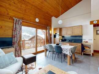 Experience cozy living in this charming mountain chalet, featuring a spacious open-plan living and dining area with a rustic wooden ceiling and a modern kitchen.