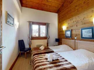 Experience cozy mountain living in this charming bedroom featuring two comfortable beds adorned with plush throws.
