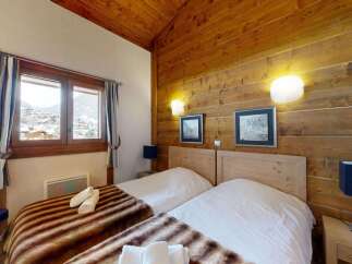 Experience cozy mountain living in this charming bedroom featuring two twin beds adorned with plush throws.