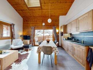 Experience cozy mountain living in this charming chalet-style apartment, featuring a spacious open-plan living and dining area with a rustic wooden ceiling and large windows offering stunning views.