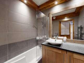 Experience modern comfort in this beautifully appointed bathroom, featuring a sleek bathtub and shower combination enclosed by a glass screen.