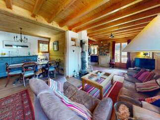 Experience rustic charm in this inviting living and dining area, featuring exposed wooden beams and a cozy fireplace.