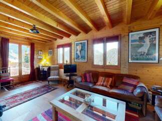 Experience rustic charm in this cozy wooden cabin living room, featuring a warm fireplace, comfortable leather sofas, and stunning mountain views through large windows.