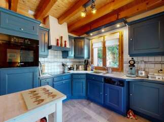 Discover this charming kitchen featuring deep blue cabinetry and a rustic wooden ceiling.