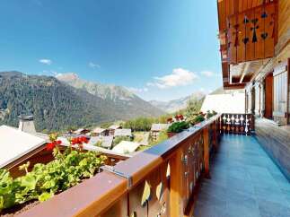 Experience breathtaking mountain views from this charming wooden balcony, adorned with vibrant red geraniums.