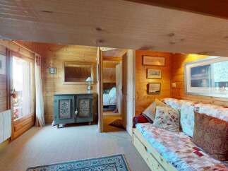 Experience cozy living in this charming wooden cabin, featuring a comfortable sofa with decorative pillows and a patchwork quilt.