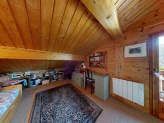 This charming attic room features a cozy bed, ample bookshelf space, and a functional desk area, perfect for a home office or a quiet retreat.
