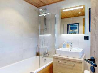Experience modern comfort in this beautifully appointed bathroom, featuring a sleek bathtub with a glass enclosure and a stylish vanity with a vessel sink.