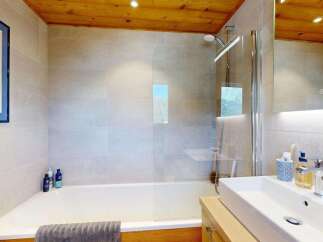 Experience modern comfort in this beautifully appointed bathroom, featuring a sleek bathtub with a glass shower screen and a stylish vanity with a vessel sink.