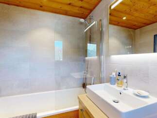 Experience modern comfort in this beautifully appointed bathroom, featuring a sleek bathtub and shower combination with a glass enclosure.