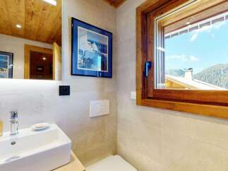 Experience luxury mountain living with this stunning bathroom featuring a modern sink, elegant fixtures, and a large window offering breathtaking views of the surrounding alpine landscape.