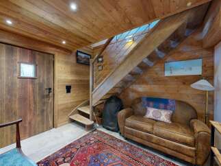 Experience rustic charm in this cozy mountain retreat, featuring warm wood paneling throughout and a striking wooden staircase leading to the upper level.