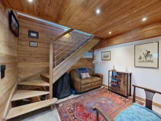 Experience rustic charm in this cozy mountain retreat, featuring warm wood paneling throughout and a striking wooden staircase with modern metal railings.