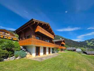 Experience luxury mountain living in this stunning chalet, featuring intricate wooden balconies and a picturesque setting.