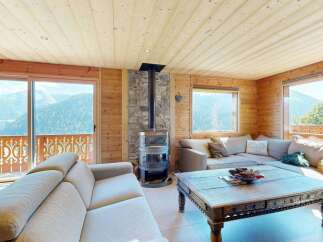 Experience breathtaking mountain views from this stunning living room, featuring a cozy wood-burning stove and expansive windows.
